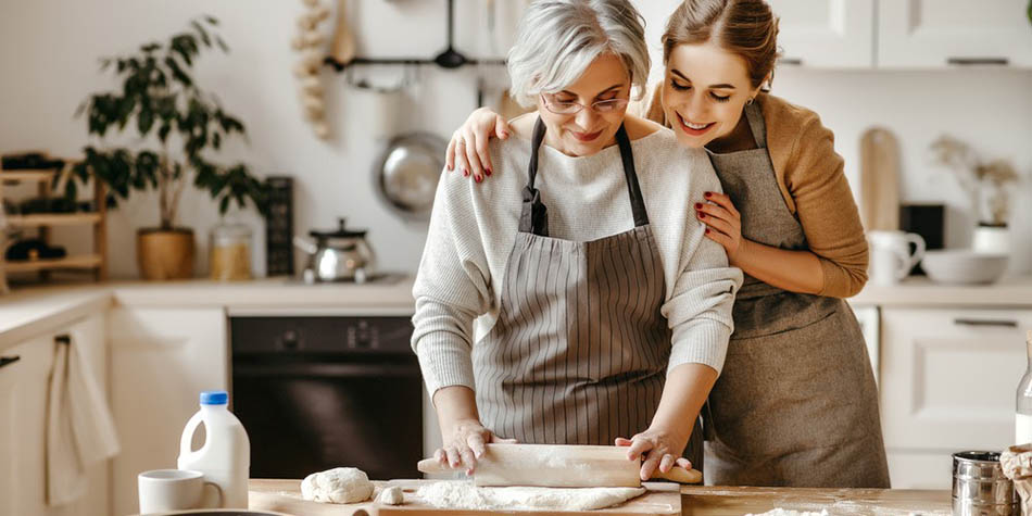 A grandmother and granddaughter roll out bread for a Thanksgiving dish.