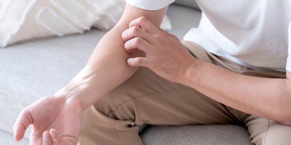 A man scratches his arm.